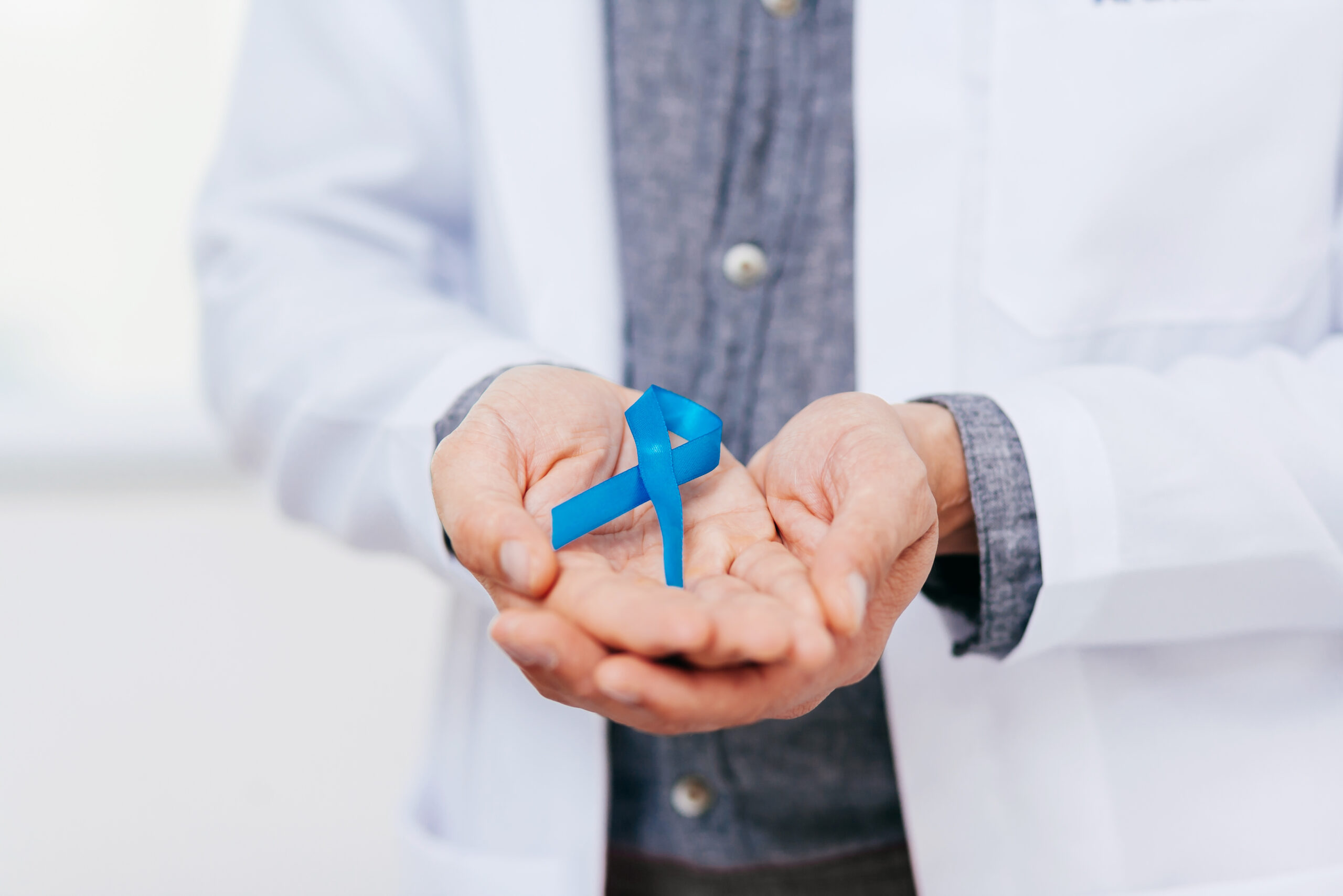 Prostate Cancer Awareness. Doctor man holding light Blue Ribbon for supporting people living and illness. Men Healthcare and World cancer day concept