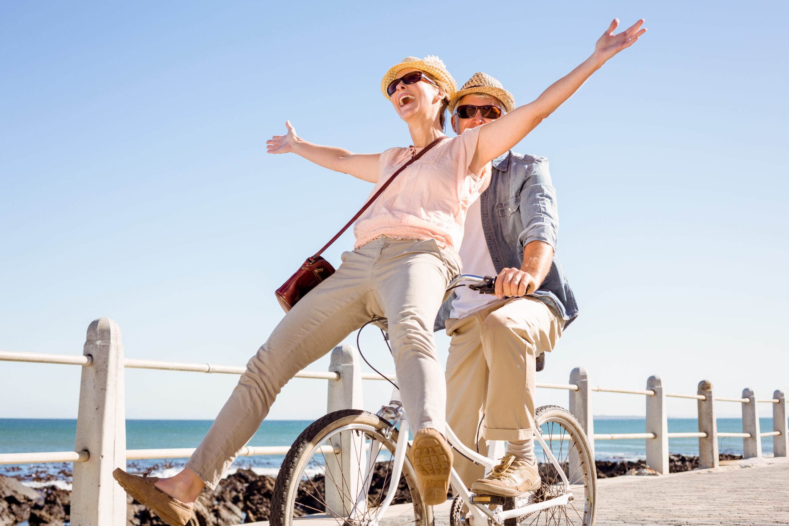 Happy casual couple going for a bike ride on the pier